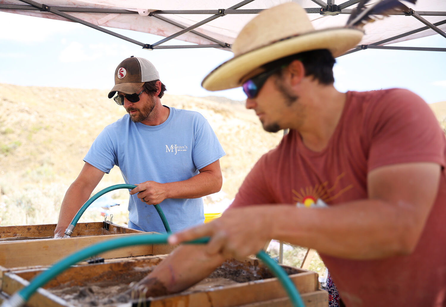 Spencer Pelton, left, and Tyson Arnold use hoses to wash away sediment